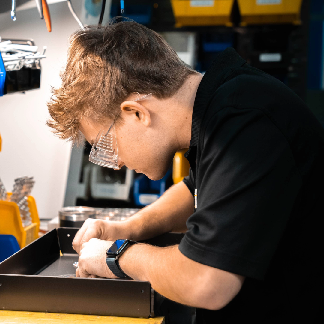 A WiLL teammate wearing safety glasses and assembling a lighting fixture